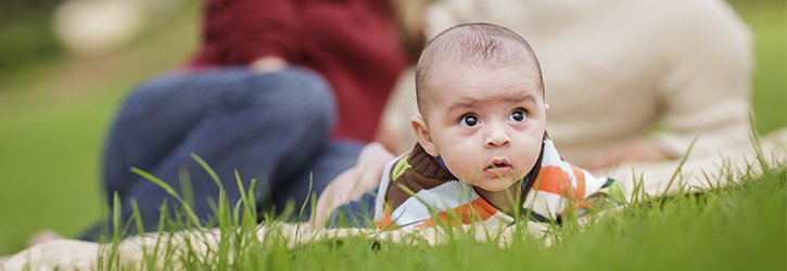 Baby in grass with mom and dad who used our money back IVF guarantee | Tennessee Reproductive Medicine | Chattanooga