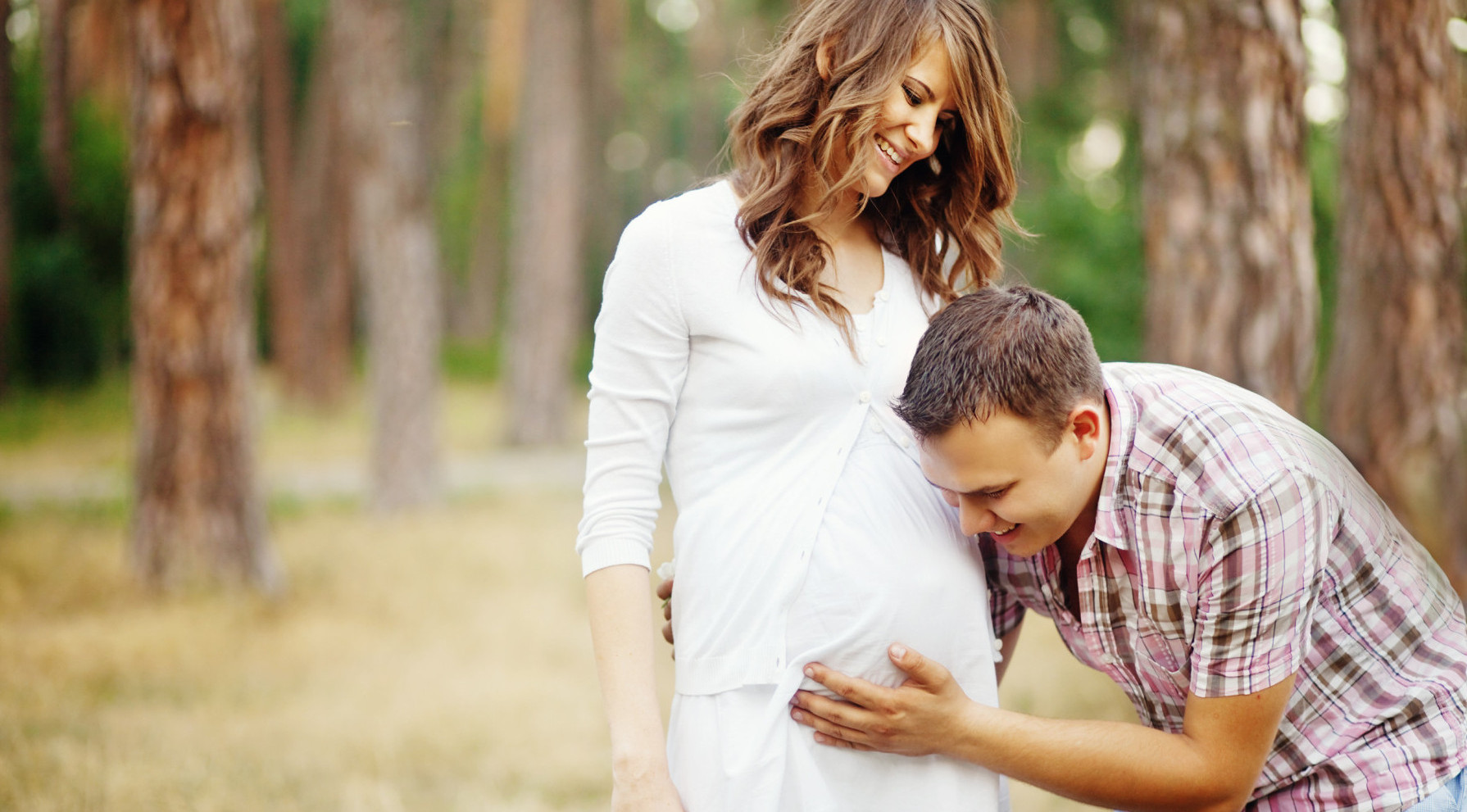 Husband listening to his pregnant wife's belly, one of our fertility success stories | Tennessee Reproductive Medicine | Chattanooga