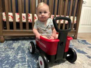 Eight-month-old TRM baby in a red wagon | IVF journey